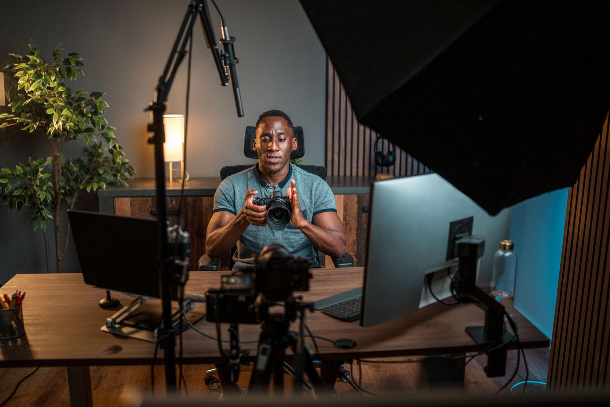 A creator at a multi-camera desk setup, reviewing a shot on a monitor