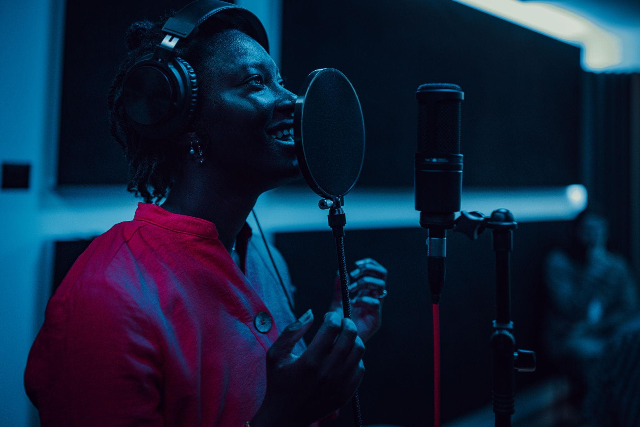 A creator singing into a studio microphone under blue stage lighting